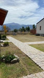 a brick walkway in a yard with mountains in the background at Cabañas La Suyana in Tafí del Valle