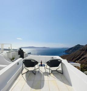 een patio met 2 stoelen en een tafel op het dak bij Firalia, Casa in Rock Suites in Fira