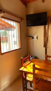 une table à manger avec une télévision et une fenêtre dans l'établissement Cabañas La Suyana, à Tafí del Valle