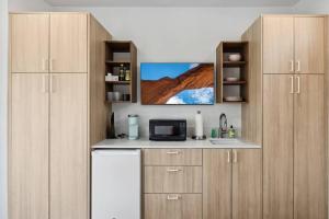 een keuken met houten kasten, een wastafel en een magnetron bij Modern 2-bedroom Apartment - 80 Walkscore! in Phoenix +9 foto's