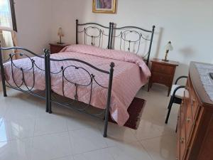 una camera da letto con un letto nero e una coperta rosa di S'Altura, dall'alto di Nuoro a Nuoro
