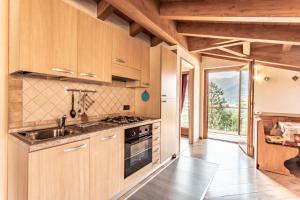 uma cozinha com armários de madeira, um lavatório e um fogão em Casa Panorama - Ledro House em Pieve Di Ledro