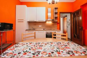 uma cozinha com paredes cor de laranja e uma mesa com uma colcha florida em La Quiete - Lakeside Leisure & Business em Arona
