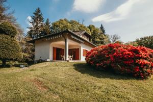 uma pequena casa branca com um arbusto de flores vermelhas em La Quiete - Lakeside Leisure & Business em Arona