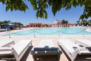 una gran piscina con 2 tumbonas frente a ella en Villa Ginkò 10 posti Letto Torre Lapillo Resort 900 Mt dal Mare, en Torre Lapillo 36 fotos más