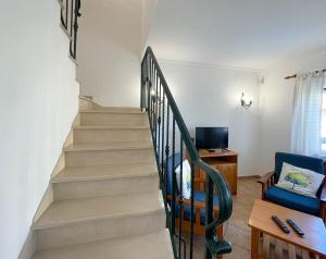 a staircase in a living room with a blue chair at Moradia T3 Aguia Marina, com piscina e BBQ in Páteo