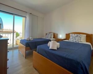 a bedroom with two beds and a large window at Moradia T3 Aguia Marina, com piscina e BBQ in Páteo +24 photos