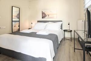 sypialnia z dużym białym łóżkiem i biurkiem w obiekcie Aellō luxury apartments w mieście Markopoulo Mesogaias
