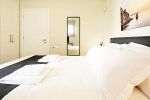 a bedroom with a bed with white sheets and a mirror at Aellō luxury apartments in Markopoulo