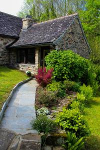 a stone house with a walkway in front of a yard at TY La Source in Plestin-les-Grèves