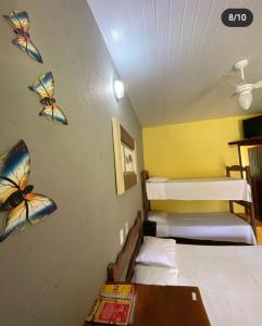 a room with three beds with butterflies on the wall at Pousada Embaubas in Serra do Cipo