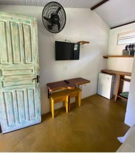 Habitación con mesa, ventilador y puerta en Pousada Embaubas, en Serra do Cipo