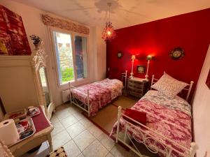 1 Schlafzimmer mit 2 Betten und einer roten Wand in der Unterkunft L Ancien Moulin à Huile in Tuchan