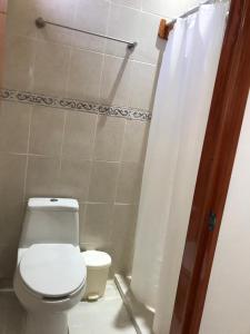 a bathroom with a toilet and a shower curtain at Hotel Cosoleacaque Centro in Cosoleacaque