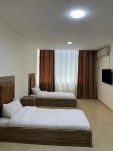 a hotel room with three beds and a television at Rayan Hotel Suites in Amman