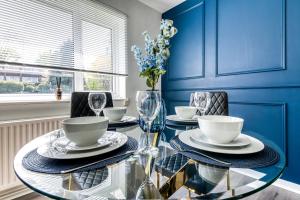 uma sala de jantar azul com uma mesa de vidro e cadeiras em Contemporary 4 bedroom detached house with parking and city links em Croydon