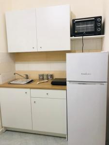 a white kitchen with a microwave and a refrigerator at Al Corso 146 in Torre del Greco