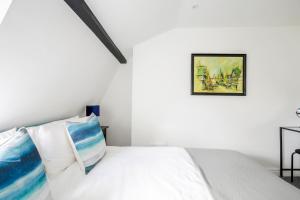 een witte slaapkamer met een bed met blauwe en witte kussens bij Chester Stays - Beautiful loft apartment with parking in Chester
