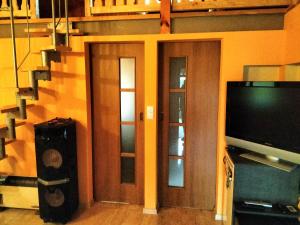 a living room with two doors and a television at Domek nad jeziorem in Osieczna