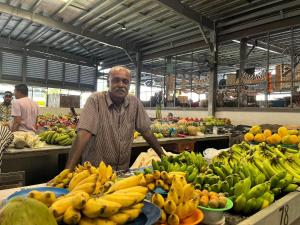 a man standing in a market with a bunch of bananas at Libby's Vacation Rental 2 Bed Home 1-4 Guests in Nadi