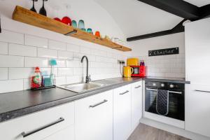 een keuken met witte kasten en een wastafel bij Chester Stays - Beautiful loft apartment with parking in Chester