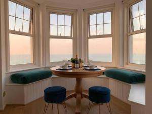 a dining room with a table and three windows at STUNNING SEA VIEWS BEACHFRONT 2 BED in Kent