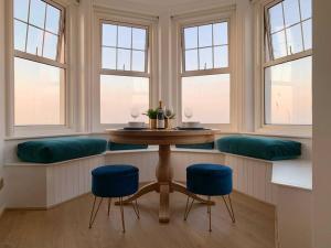 a dining room with a table and blue stools at STUNNING SEA VIEWS BEACHFRONT 2 BED in Kent