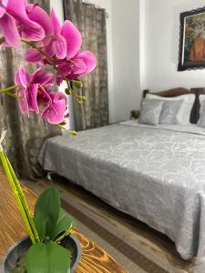 a bedroom with a bed and a vase with purple flowers at Hotel Omer in Berat