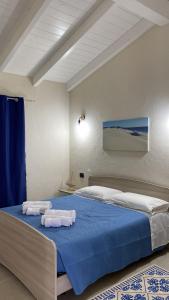 1 dormitorio con 1 cama con toallas en Is Arenas Biancas Agriturismo, en Teulada