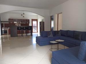 a living room with a blue couch and a kitchen at Villa faravohitra in Antananarivo