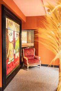 ein Wohnzimmer mit einem Stuhl und einem Gemälde in der Unterkunft Naâd Hotel Sarlat Centre Ville in Sarlat-la-Canéda