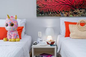 un animal de peluche está sentado en dos camas en un dormitorio en Hotel Ponta Verde Maceió en Maceió