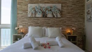 Una cama blanca con almohadas blancas y flores. en Almirante Apartment Sea Views, en Mijas