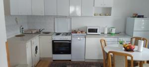 a kitchen with white appliances and a table with a bowl of fruit at Villa Bella in Ilidža