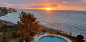 puesta de sol sobre el océano con piscina en Almirante Apartment Sea Views, en Mijas