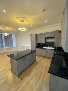 a large kitchen with black counter top and wooden floors at Luxury Apartment APT4 in Wolverhampton