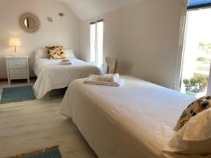 a white bedroom with two beds and a mirror at Exclusivo ático Baiona Carabela Pinta in Baiona