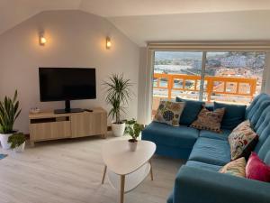 a living room with a blue couch and a tv at Exclusivo ático Baiona Carabela Pinta in Baiona