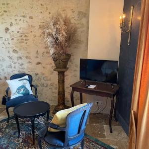 uma sala de estar com uma secretária e cadeiras e uma televisão em La Maison d'Horbé em La Perrière