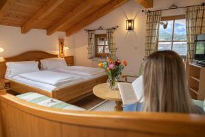 a woman sitting in a room with a bed and a table at Gästehaus Almblick in Schönau am Königssee