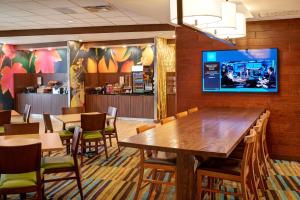 ein Restaurant mit Tischen und Stühlen und einem TV an der Wand in der Unterkunft Fairfield Inn & Suites by Marriott Detroit Troy in Troy