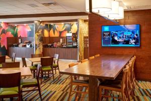 un restaurante con mesas y sillas y TV en la pared en Fairfield Inn & Suites by Marriott Detroit Troy, en Troy