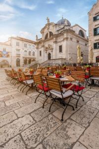 une rangée de tables et de chaises devant un bâtiment dans l'établissement Palacio Celeste, à Dubrovnik