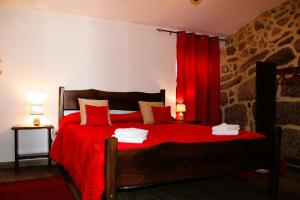 a bedroom with a red bed with a red curtain at Casa da Cuca in Campo do Gerês
