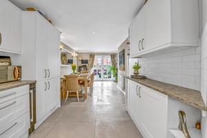 a kitchen with white cabinets and a dining room at Stylish 3 bedroom townhouse for 5 guests, set in the medieval grid with off street parking in Bury Saint Edmunds