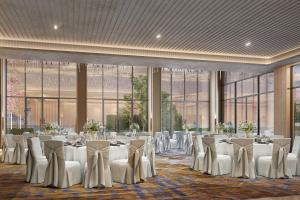 a banquet hall with white tables and chairs and large windows at Courtyard by Marriott Ahmedabad Sindhu Bhavan Road in Ahmedabad