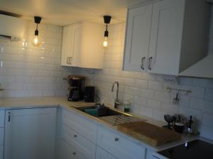 a kitchen with white cabinets and a sink at Stenkullens gårdshus in Borensberg