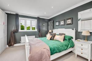 een slaapkamer met een wit bed en een groene deken bij Stylish 3 bedroom townhouse for 5 guests, set in the medieval grid with off street parking in Bury Saint Edmunds