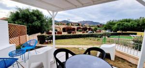 a patio with chairs and tables and a view of a yard at La casa al mare, Pittulongu in Olbia