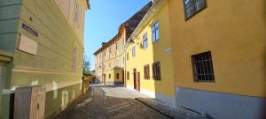 an alley in an old town with yellow buildings at Ica House Central in Sibiu